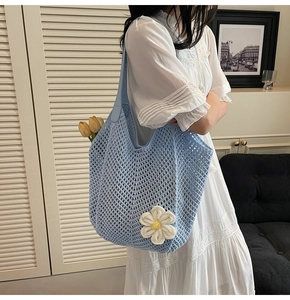 Close-up of light blue crochet tote bag with white daisy flower and leather handle