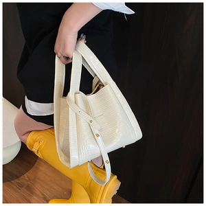 Close-up of cream crocodile pattern handbag with golden hardware and brand logo