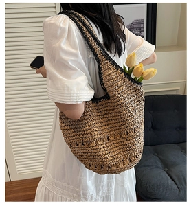 Detail of large woven straw tote bag with black contrast handles and textured finish
