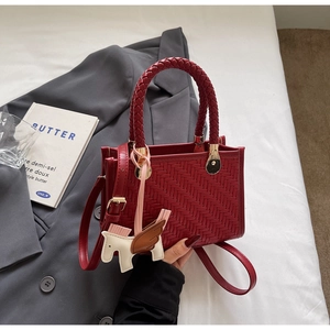 Détail macro d'un sac cabas tissé rouge avec charm poney et bandoulière élégante