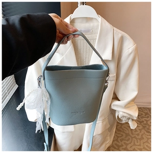 Detail of light blue bucket bag in litchi grain leather with pearl lace charm