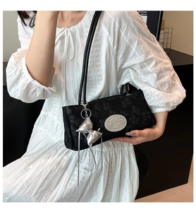 Dettaglio borsa a spalla in jacquard nero con ciondolo a fiocco argento e placca logo