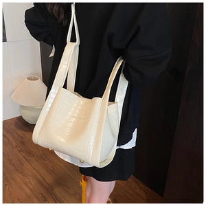 Detail of cream crocodile embossed tote bag featuring sturdy handles and metal feet