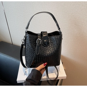 Détail du sac seau noir tressé avec texture brillante et bandoulière amovible