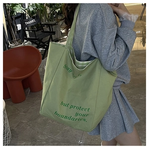 Détail du sac cabas en toile verte avec texte imprimé et doublure intérieure à carreaux