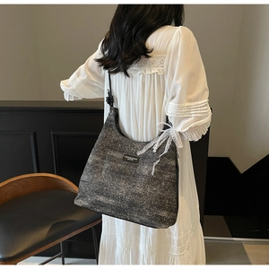 Détail du sac hobo avec nœud en dentelle et pendentif perle sur fond de robe en dentelle