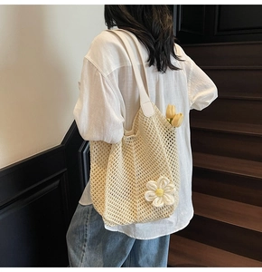 Detail view of woven hollow-out beige tote bag featuring a 3D knit sunflower charm