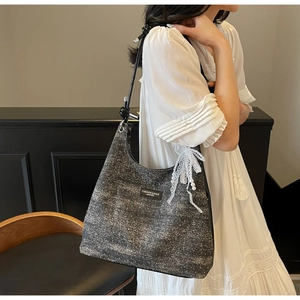 Détail du sac bandoulière en tweed gris foncé avec nœud en dentelle et perle bijou