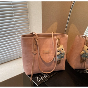 Detail of pink woven tote bag with slim straps, teddy bear charm, and premium texture