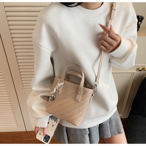 Modella indossa borsa a tracolla intrecciata beige con ciondolo argento e pelle