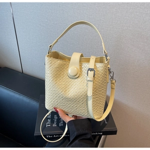 Détail du sac seau tressé jaune clair avec texture point de croix et fermoirs en métal argenté