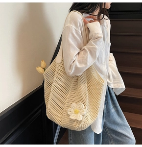 Detail of crochet straw tote bag with daisy flower applique and textured woven pattern