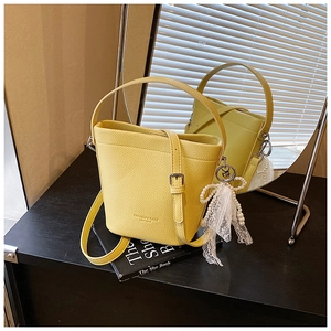 Detail of yellow pebble leather bucket bag with lace pearl bow charm and top handle