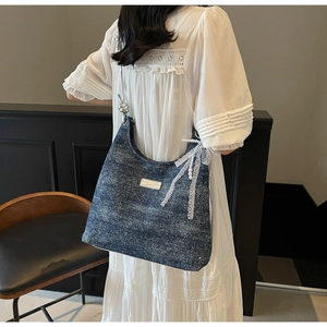 Détail du sac d'épaule en denim bleu avec nœud en dentelle blanche, perles et paillettes
