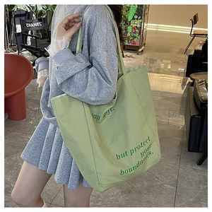 Détail du sac cabas en toile vert clair avec slogan stay soft but protect your boundaries