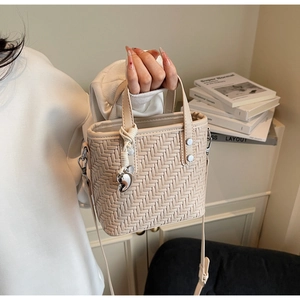 Dettaglio della borsa tote intrecciata bianco crema con trama a V e ciondolo a cuore argento