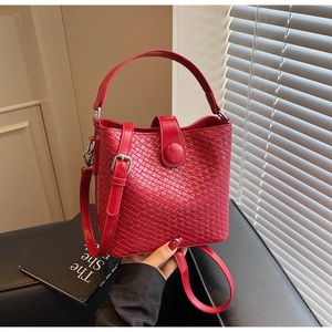 Détail du sac seau rouge tressé avec texture cuir fin et fermeture à boucle en métal