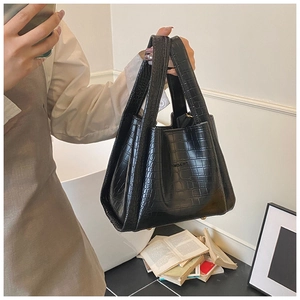 Close-up of black crocodile pattern tote bag with polished finish and top handle detail