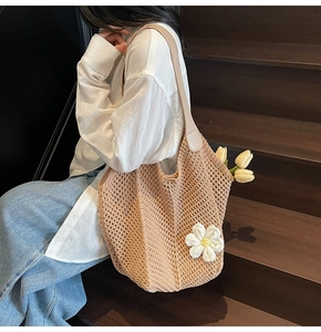 Detail of hand-woven crochet tote bag with 3D white flower decor and leather handles