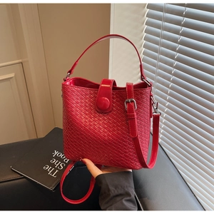 Détail de la texture tressée rouge du sac seau avec boucle métallique et poignée