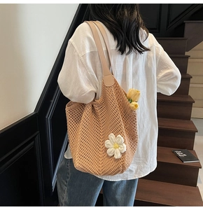 Detailed close-up of a beige woven tote bag with white floral accents on long straps