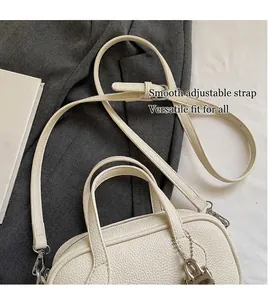 Detailed macro view showing the white pebble leather texture and metal buckle on the bag