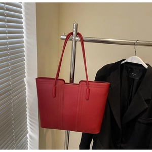 Gros plan du sac cabas rouge avec texture grainée et longues bandoulières élégantes