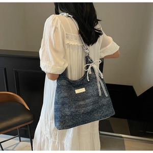 Détail du sac bandoulière en denim bleu à pois blancs avec nœuds en perles et dentelle