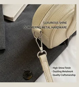 Detailed close-up of silver metal zipper and hook on cream lychee pattern leather bag