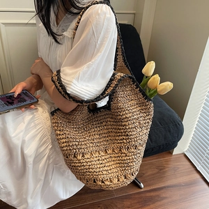 Detail of a woven straw tote bag with black contrast trim and spacious interior