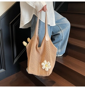 Close-up of woven straw tote bag with 3D crochet flower and leather handles