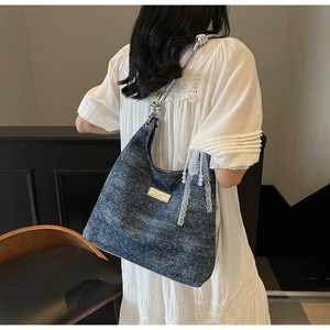 Détail du sac sous le bras en denim avec poignée argentée et breloque en perles