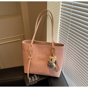 Pink tote bag detail with woven texture and a cute bear plush pendant accessory