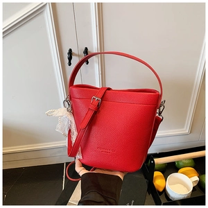 Dettaglio della borsa a secchiello rossa con texture a grana e ciondolo con perle