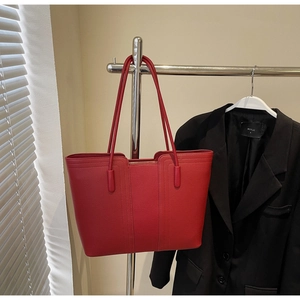 Détail du sac cabas rouge en cuir texturé avec coutures élégantes et fermeture éclair
