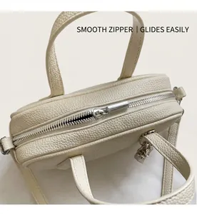 Detailed top view of a cream Boston bag with silver zipper and lychee leather texture