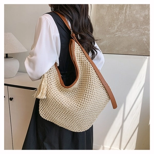 Détail du sac en paille tissé avec bandoulière en cuir et longues franges pour la plage