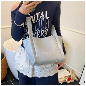 Light blue faux crocodile embossed tote bag with white logo and metal base feet