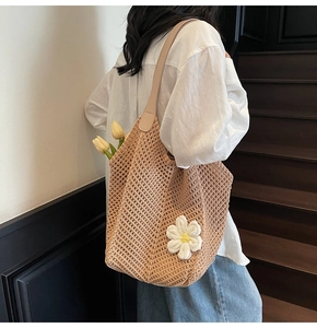 Detail view of woven straw tote bag with crochet flower and leather straps on model