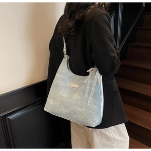 Detail of light blue underarm bag with delicate white lace bow and pearl charm accents