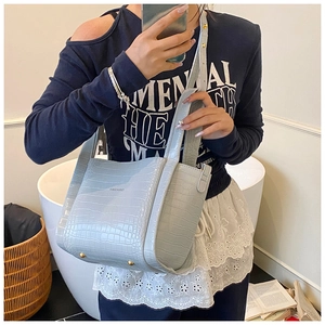 Detail of light blue crocodile pattern bucket bag with gold protective feet and brand logo