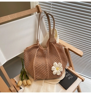 Detail of a brown woven tote bag with white floral accents on a wooden chair