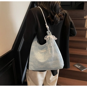 Sac hobo bleu pailleté avec nœud en dentelle et pendentif perle porté à l'épaule