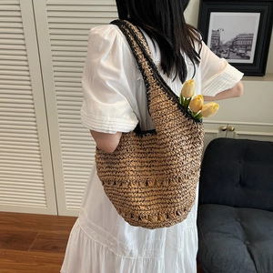 Detail of woven straw tote bag with black trim and yellow tulips in a lifestyle setting