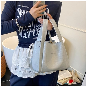 Detail of light blue-grey handbag featuring crocodile texture and HMOAIRD silver logo