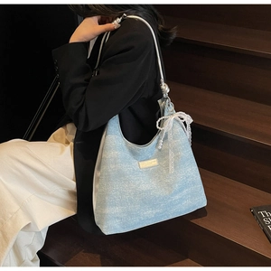 Détail d'un sac d'épaule en jean bleu clair avec boucles argentées et chaîne de perles