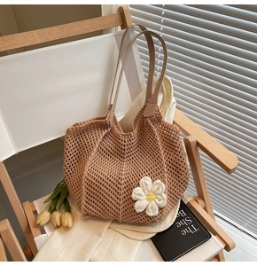 Detailed close-up of brown woven crochet tote bag with white floral charm and mesh texture