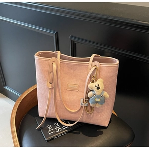 Detailed texture of pink knitted tote bag with cute teddy bear charm and brand logo