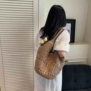 Close-up of a large woven straw shoulder bag with black trim for vacation wear