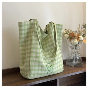 Détail du sac cabas en toile à carreaux verts et blancs avec broderie chien sur étagère